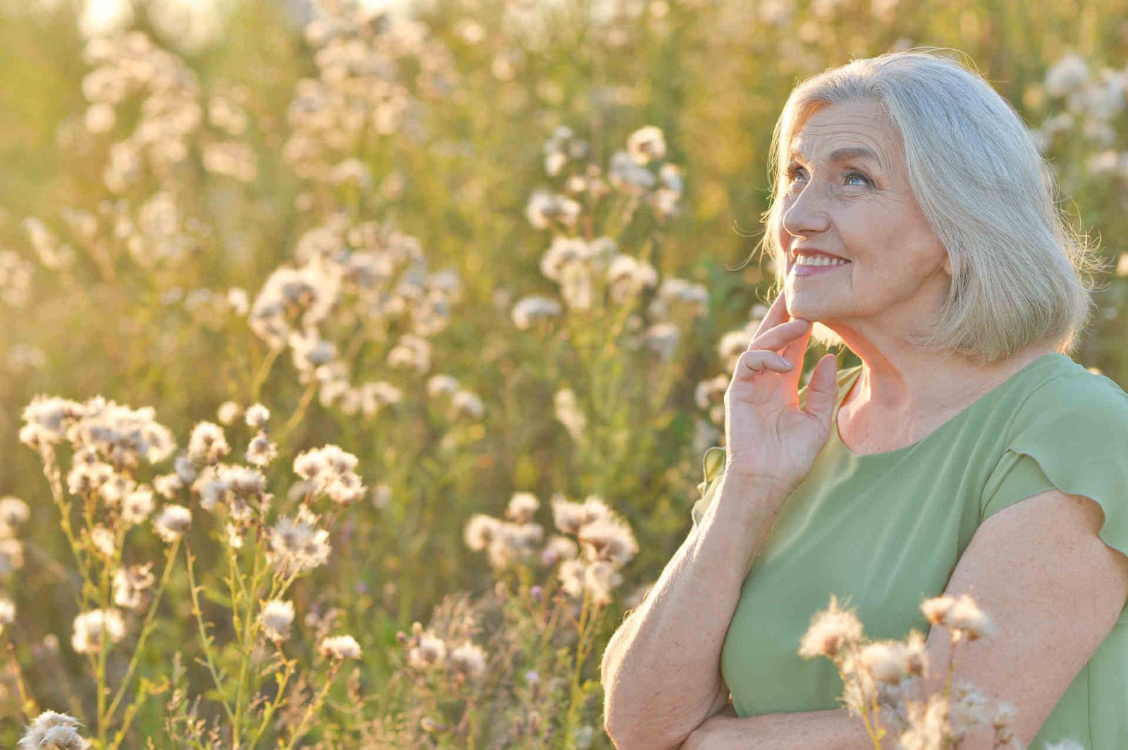 טיפול טבעי לגיל המעבר - אישה בגיל המעבר על רקע שדה פרחים