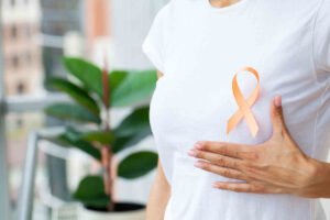 טיפול טבעי בסרטן השד - סמל של מלחמה בסרטן השד על אישה עם חולצה לבנה
